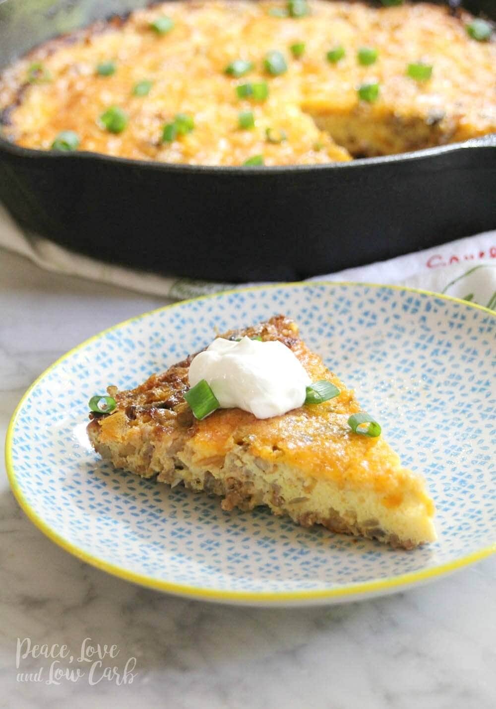 A decorative plate with a serving of low carb frittata, topped with sour cream and cream onions.