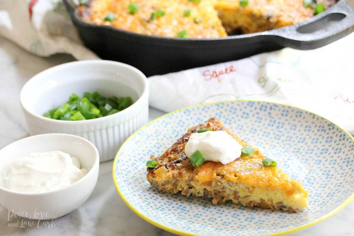 A decorative plate with a serving of low carb frittata, topped with sour cream and cream onions.