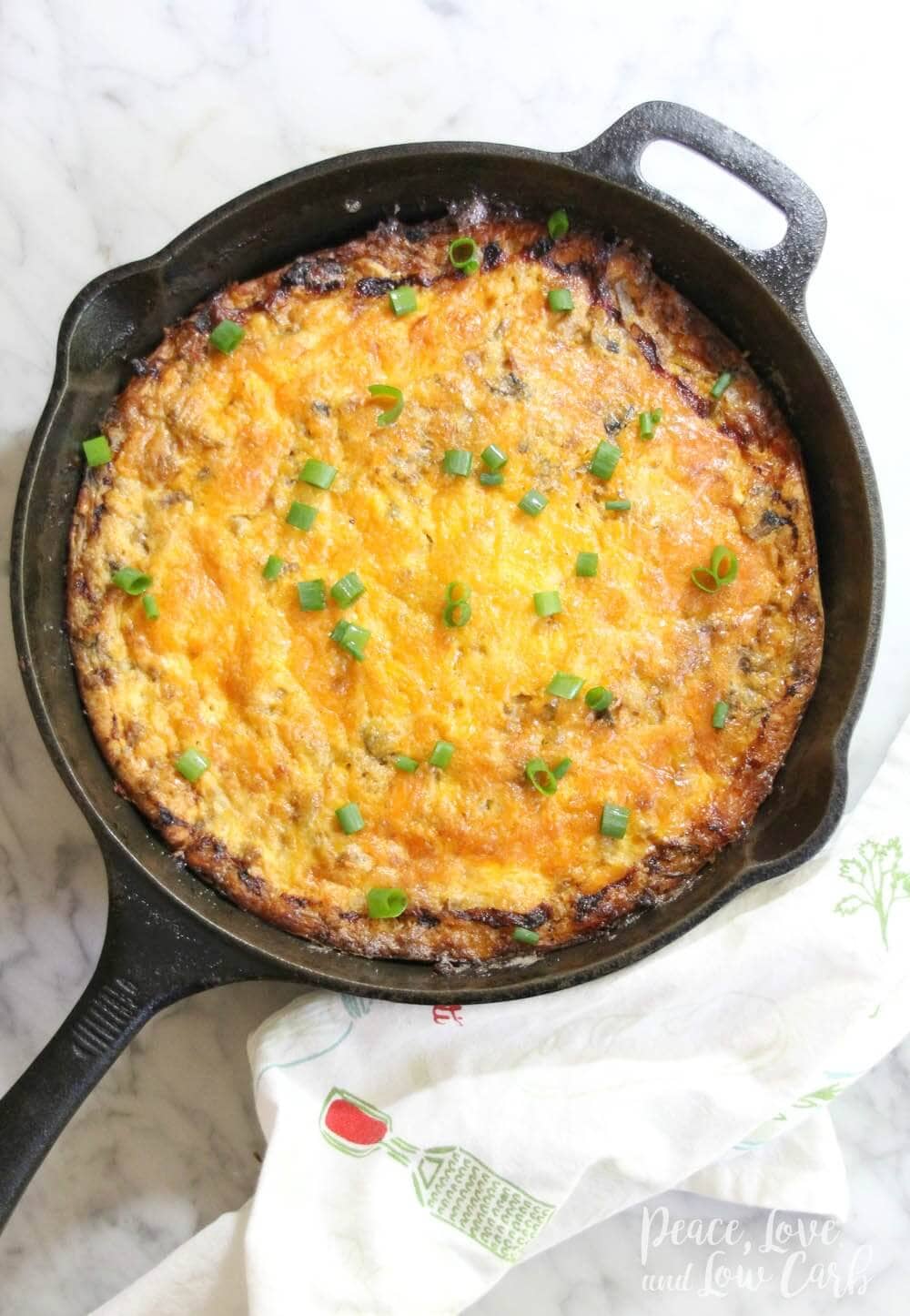 a cast iron skillet with a sausage breakfast casserole, garnished with green onions