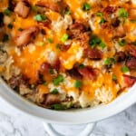 white casserole dish with a twice baked cauliflower with bacon, cheese, and green onions