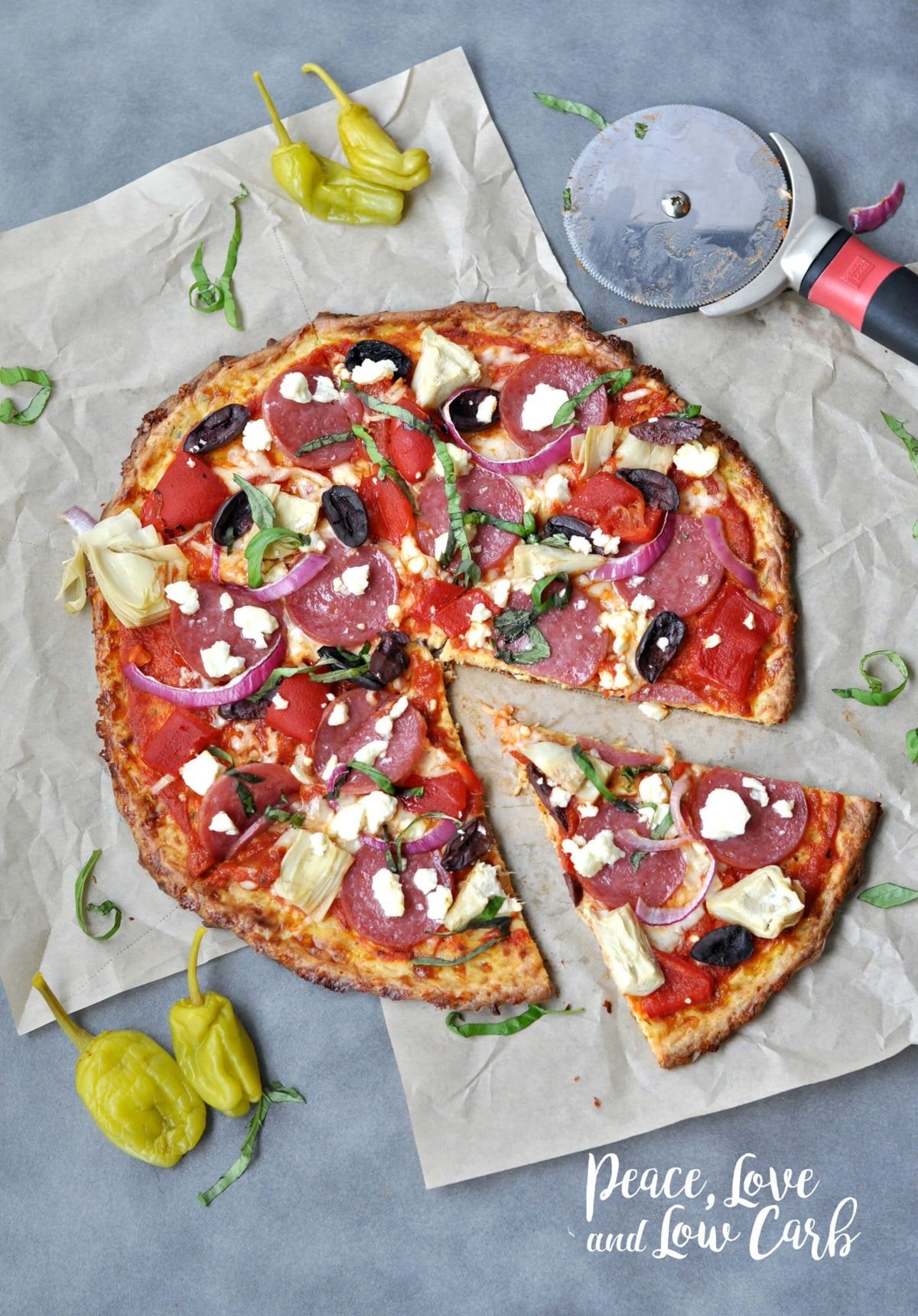 a keto greek pizza, topped with salami artichokes, olives, feta, onions, basil and peppers