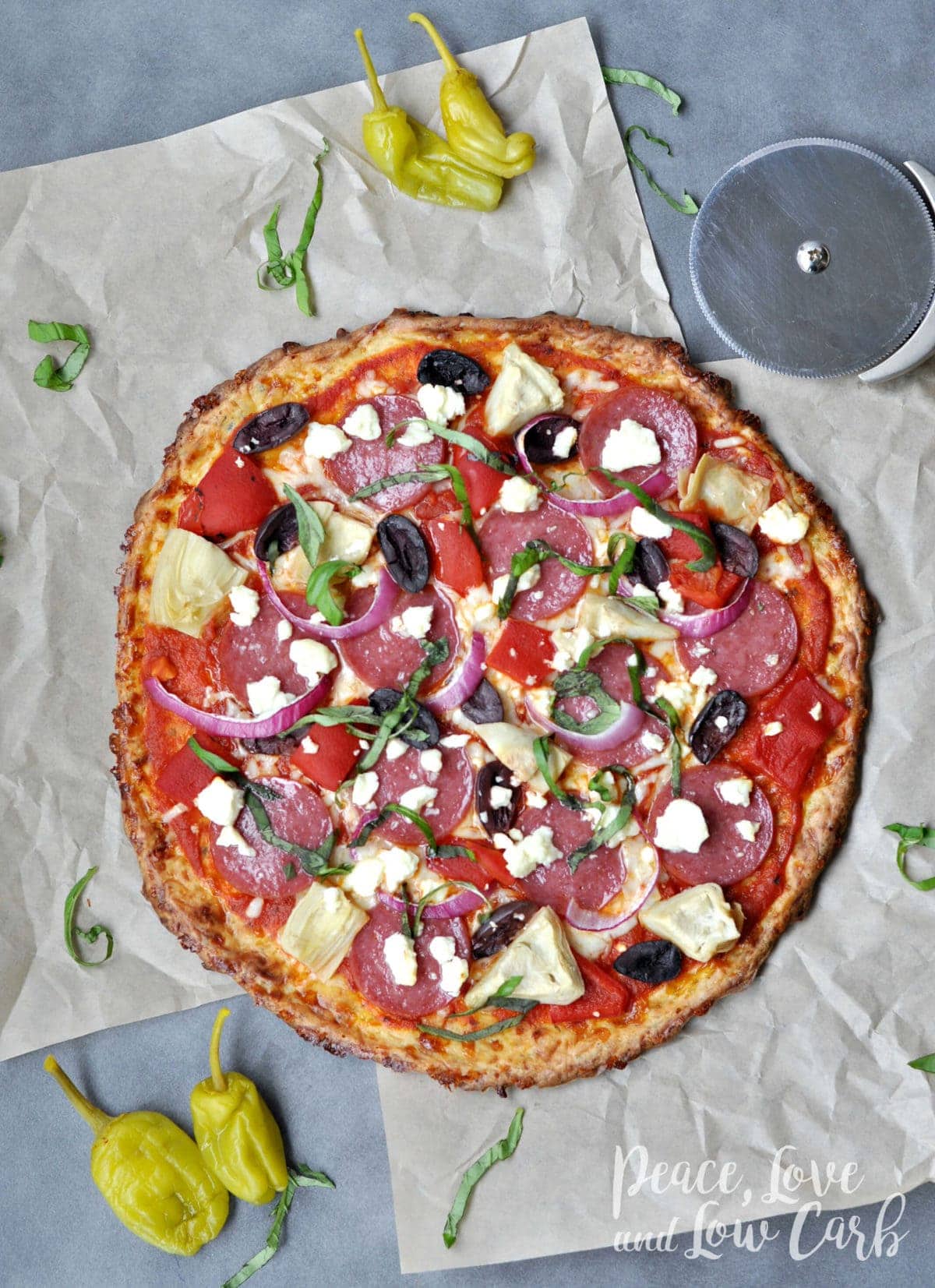 a keto greek pizza, topped with salami artichokes, olives, feta, onions, basil and peppers