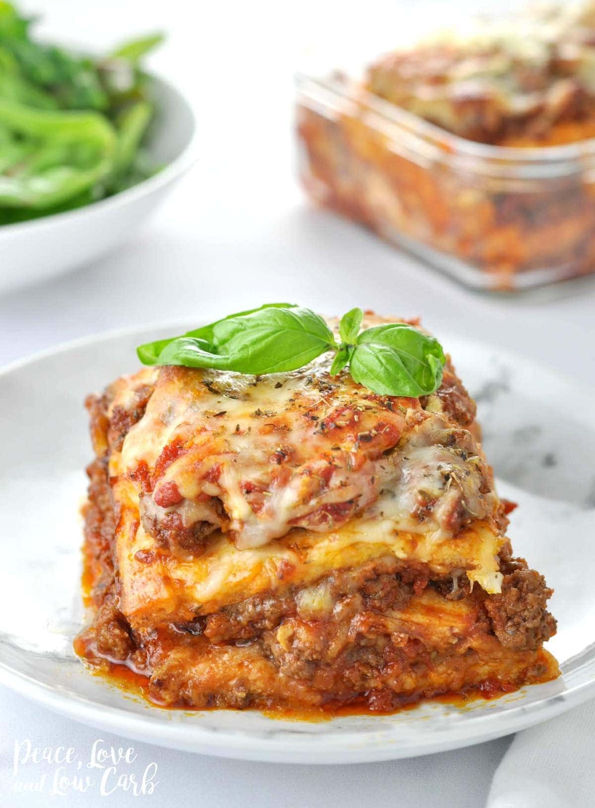 A close up photo of a low carb lasagna. Melty cheese, sauce, beef, garnished with basil