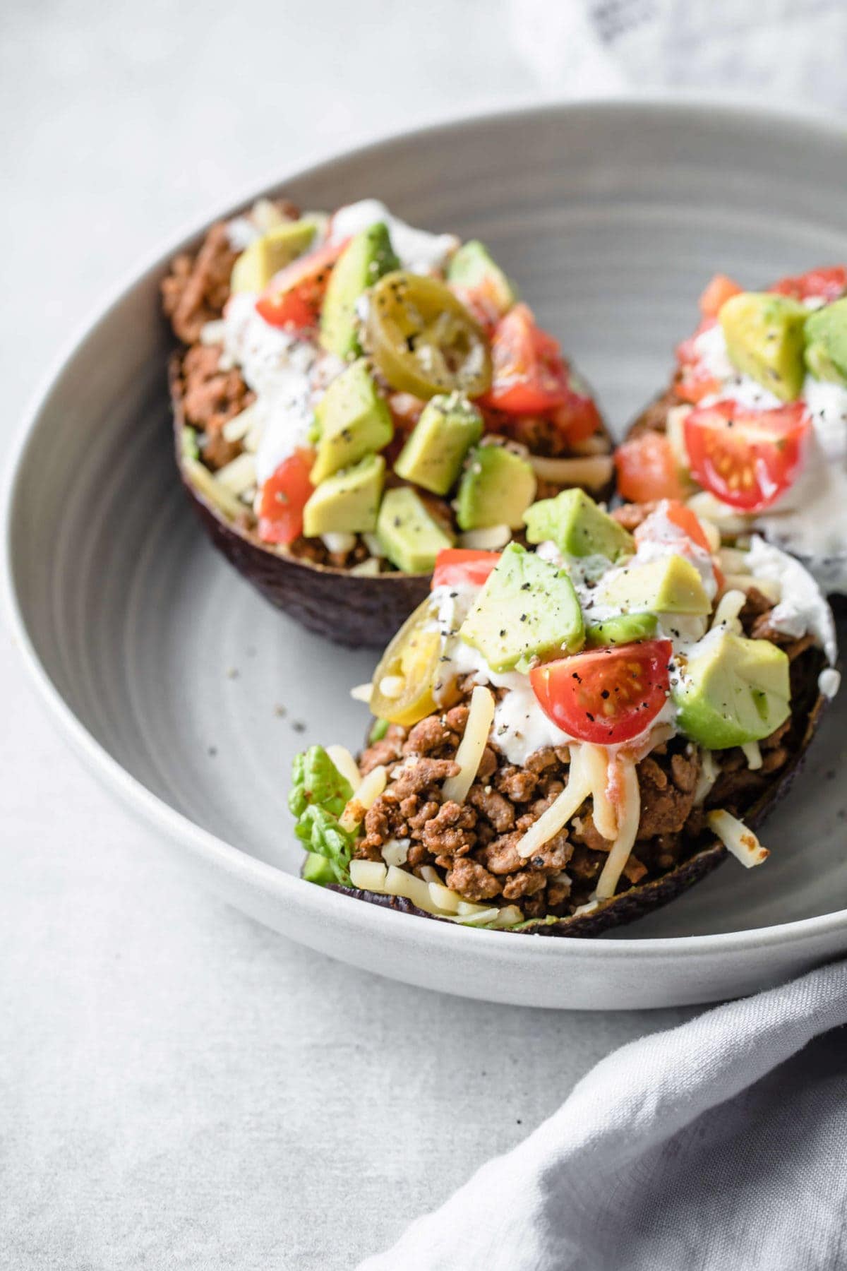 tacos served in an avocado shell with ground beef, cheese, tomatoes, avocado and sour cream 