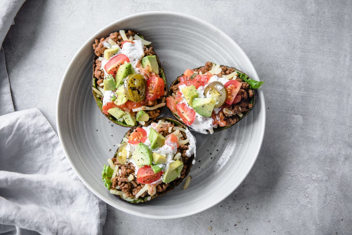 tacos served in an avocado shell with ground beef, cheese, tomatoes, avocado and sour cream 