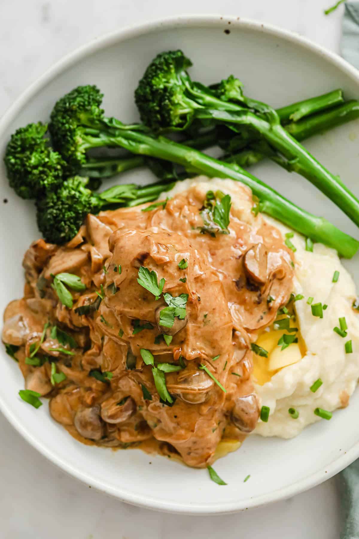creamy chicken with mushrooms and onions, plated with cauliflower mash and broccoli