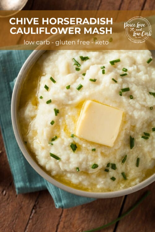 A ceramic bowl of creamy cauliflower mash, topped with melted butter and chopped fresh chives.