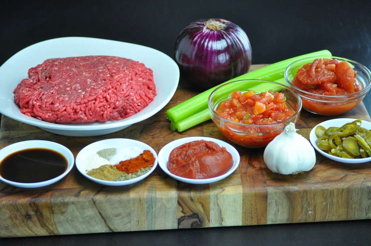 ingredients for slow cooker chili - ground beef, onion, celery, tomatoes, jalapeños, Worcestershire, tomatoes, seasonings.