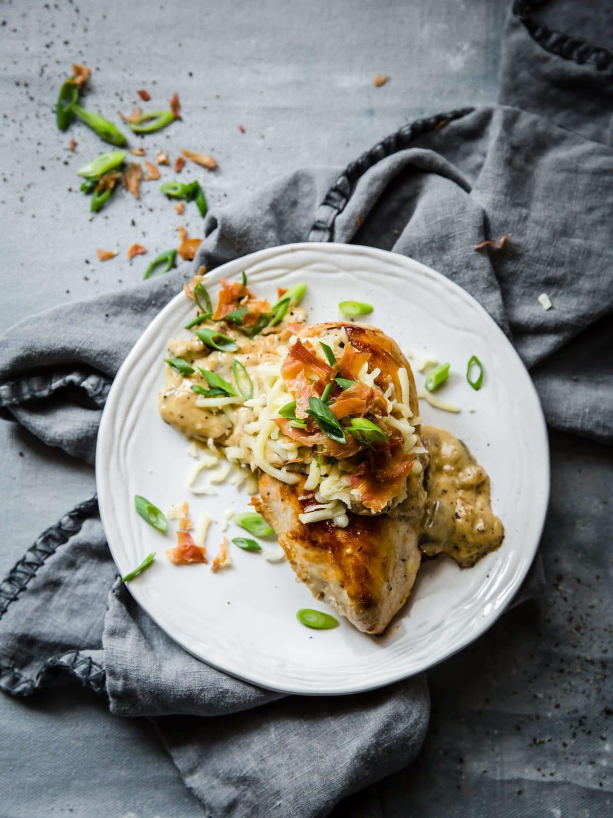 white plate with seared chicken, cheese, and a sour cream sauce with mushrooms and onions