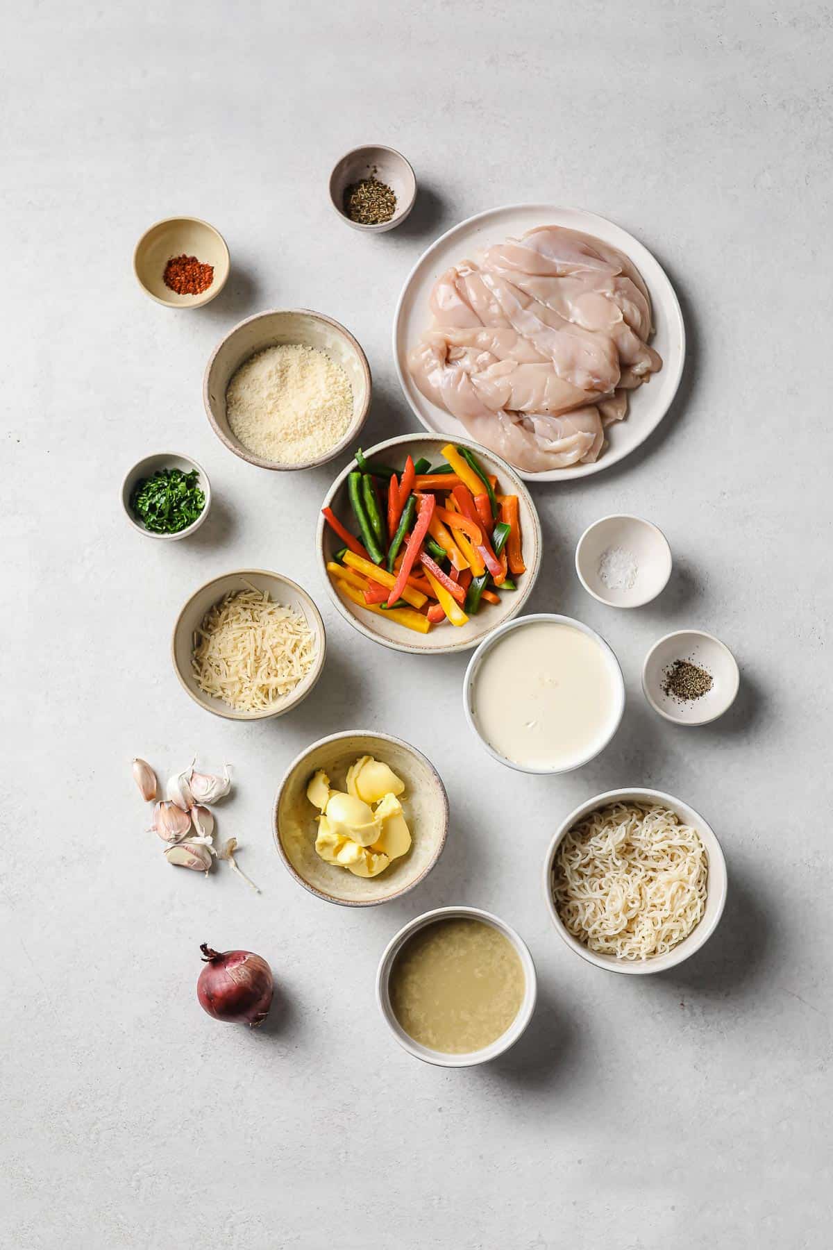 ingredients laid out in a spread - chicken, onion, peppers, cheese, garlic, butter, oil, broth, parsley, salt and pepper