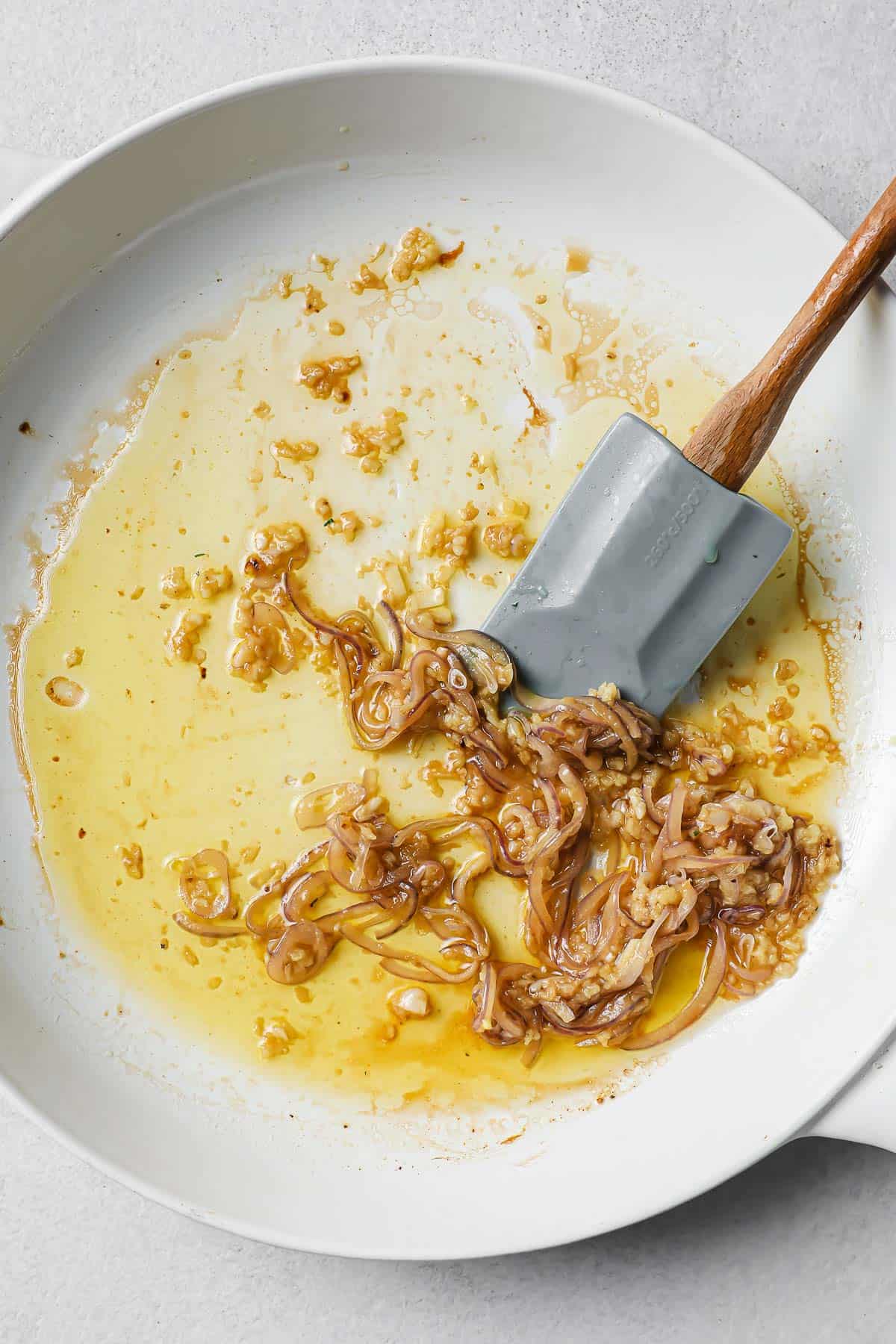 a white skillet with sautéed onions and garlic
