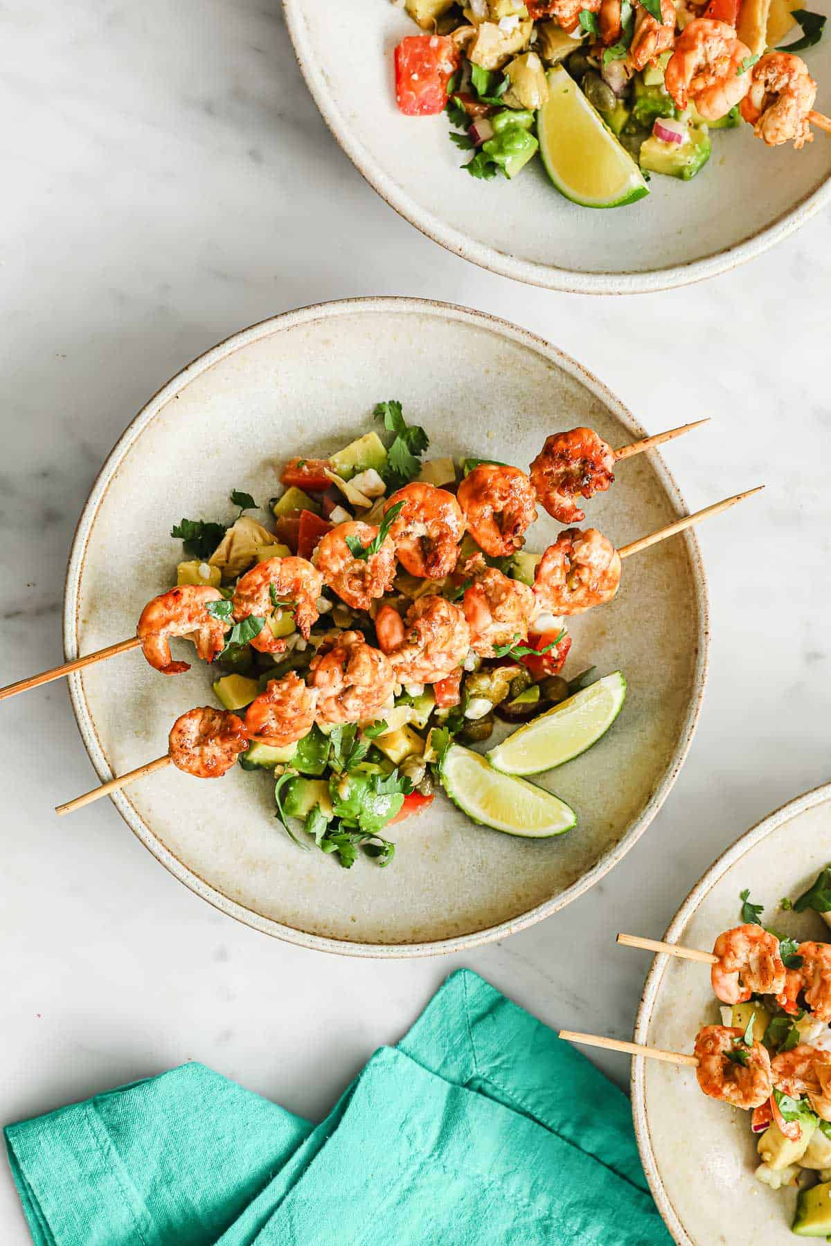 grilled prawns on top of an avocado feta salsa, plated with lime wedges