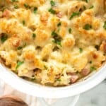 a white casserole dish full of a cheesy low carb chicken cordon blue casserole, garnished with parsley