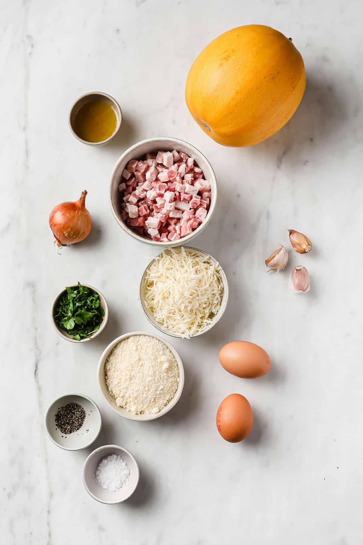 ingredients laid out to make spaghetti squash carbonara - spaghetti squash, pancetta, parmesan, egg, parsley, and onion