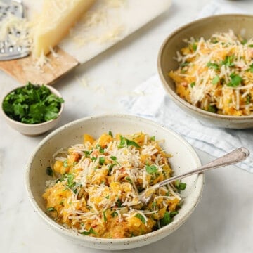 a large serving bowl, filled with spaghetti squash pasta with pancetta, parsley, and parmesan cheese