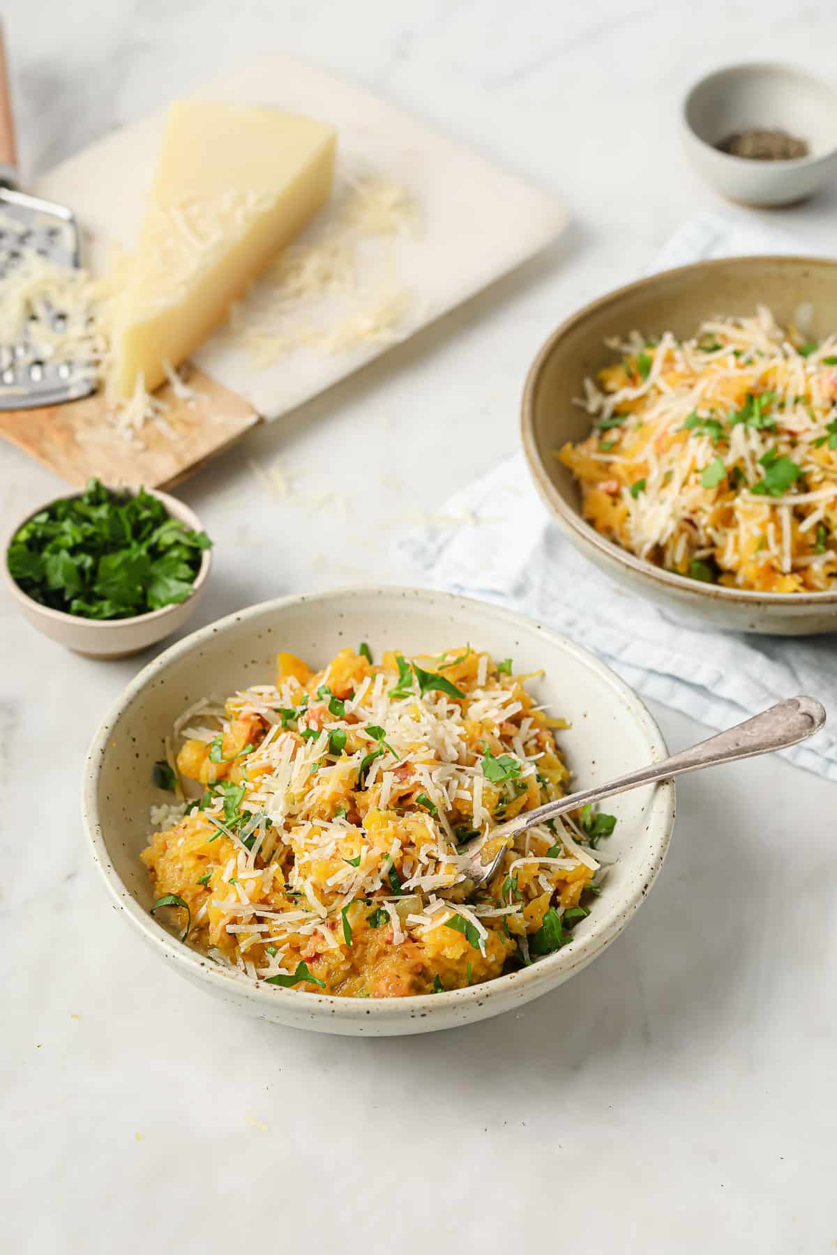 a large serving bowl, filled with spaghetti squash pasta with pancetta, parsley, and parmesan cheese