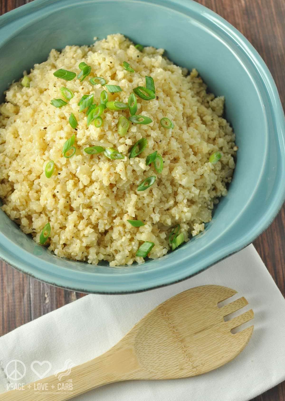 a blue serving dish with cauliflower rice served in it, topped with green onions