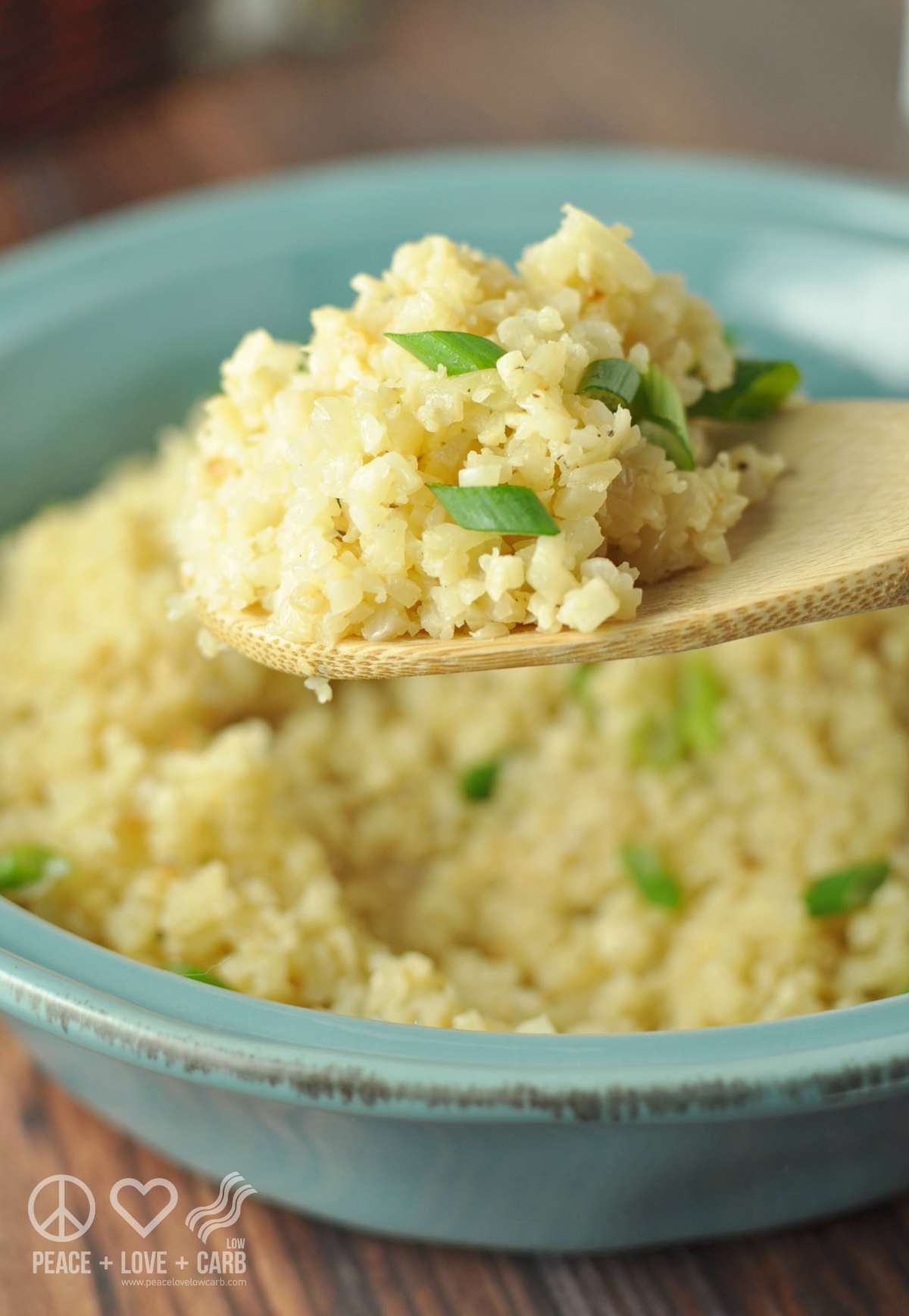 a blue serving dish with cauliflower rice served in it, topped with green onions