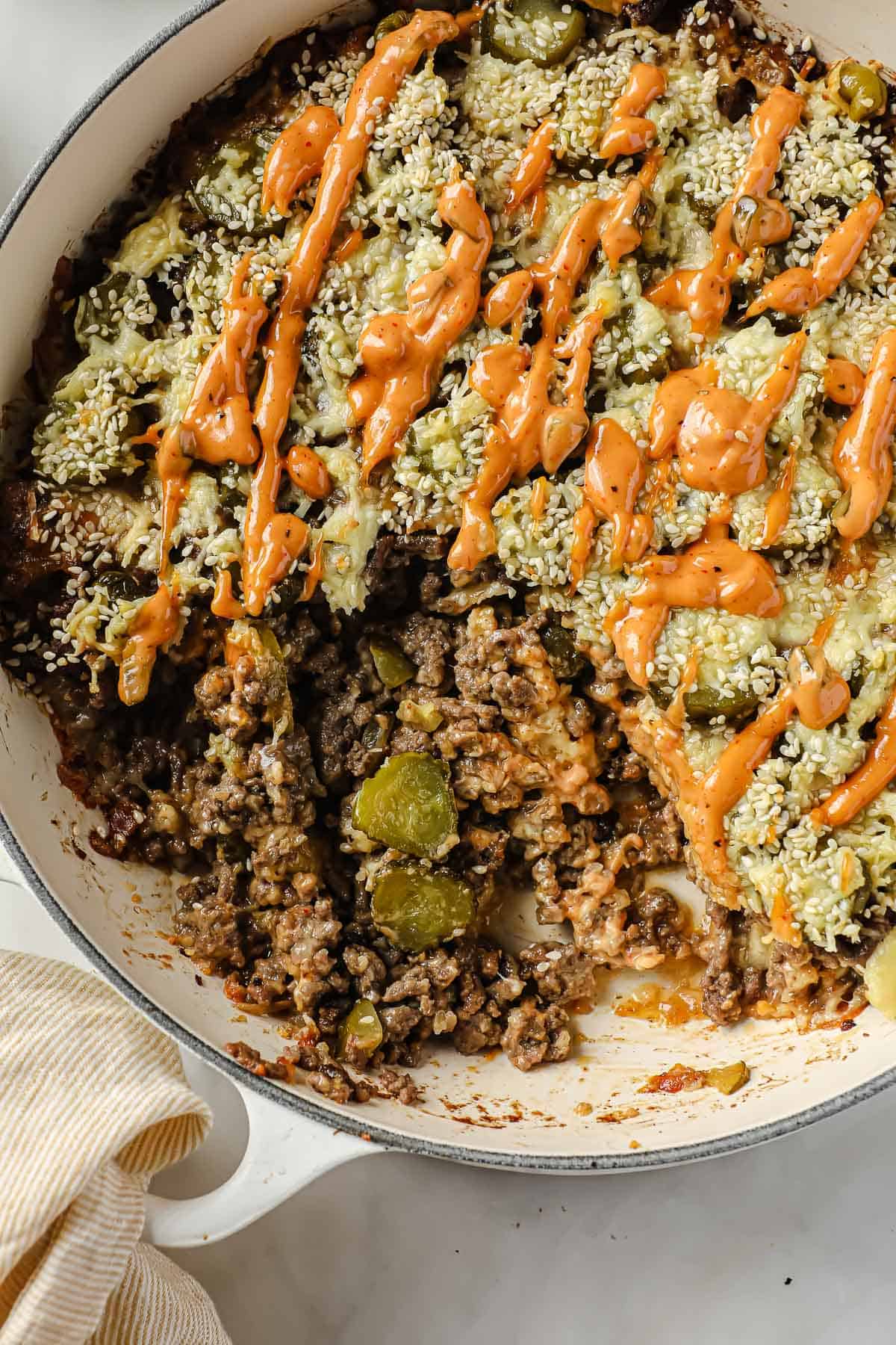 a cast iron pan, full of big Mac casserole made with ground beef, burger sauce, cheese, pickles, onions and sesame seeds
