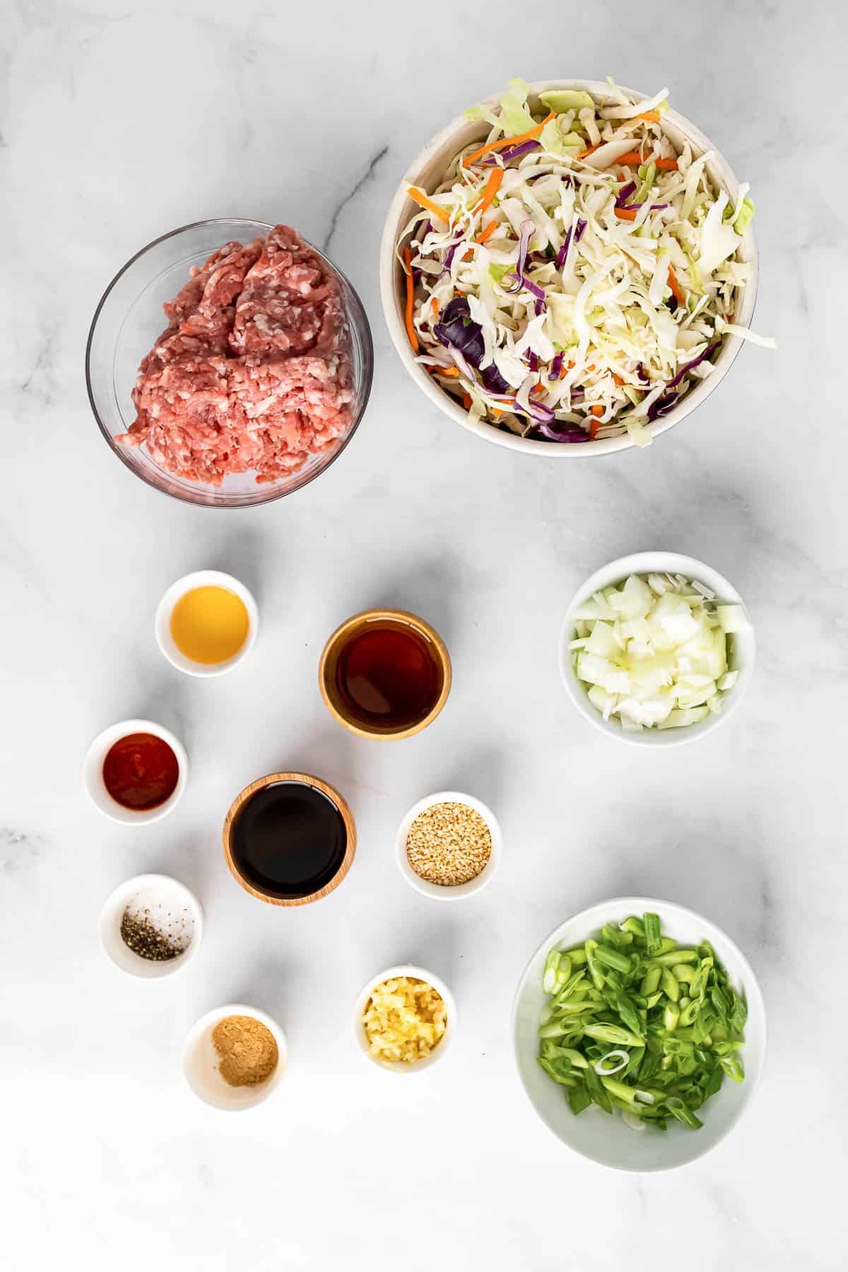 ingredients to make egg roll in a bowl - ground pork, coleslaw mix, onion, garlic, soy sauce, green onions