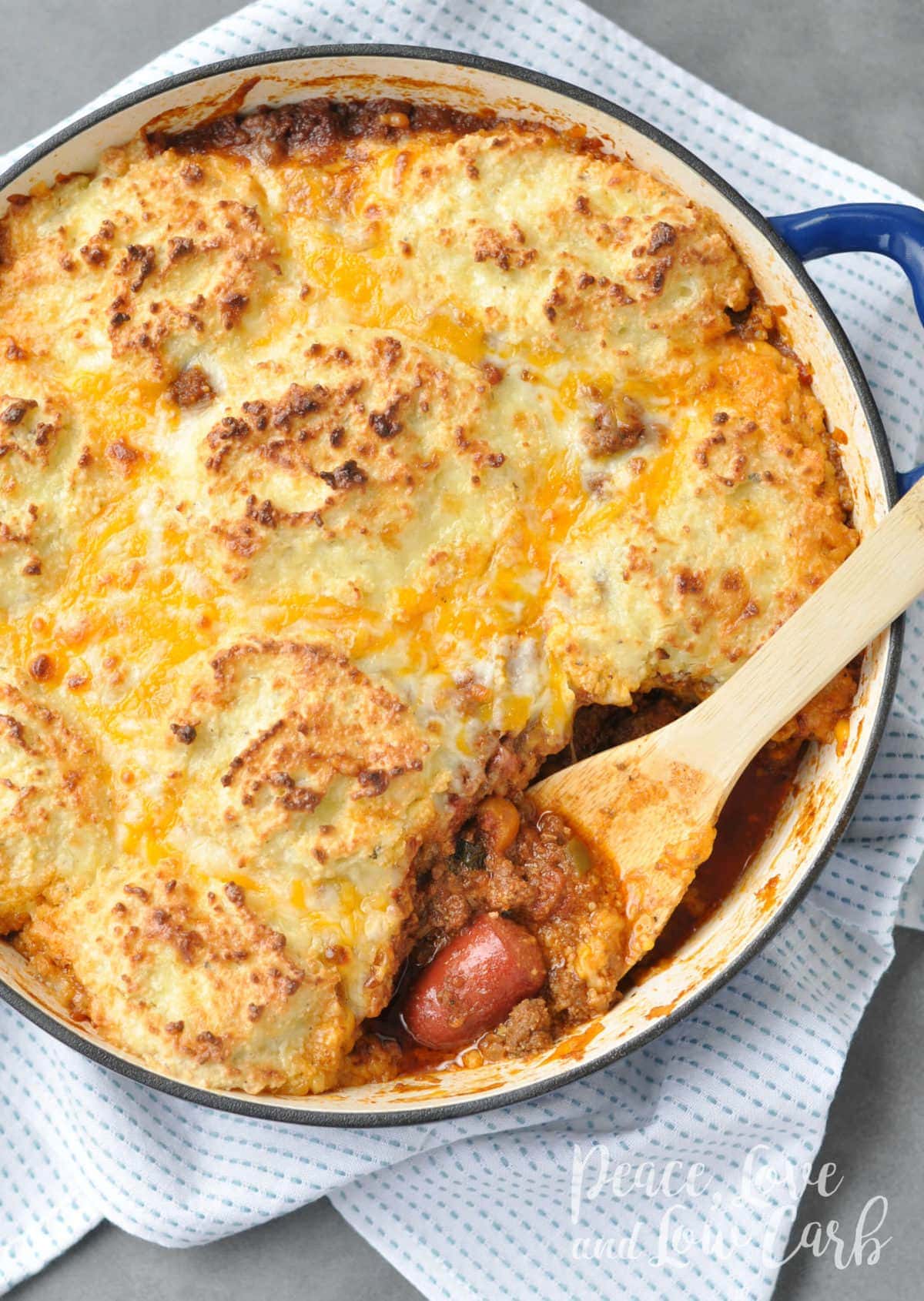 Overhead shot of a chili dog pot pie casserole in an enameled cast iron skillet.