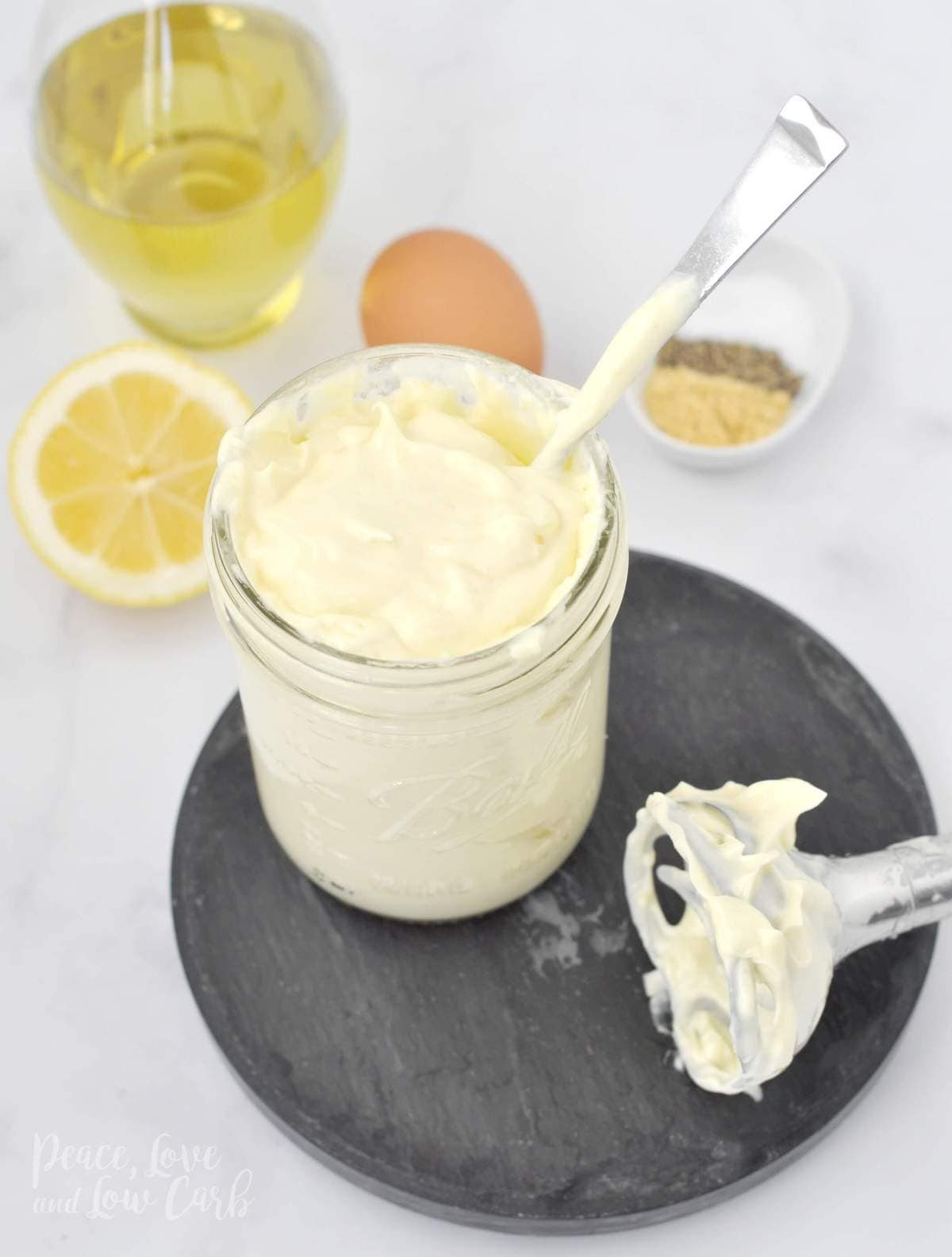 jar of homemade mayo with oil, egg, lemon, mustard, salt, pepper, and an immersion blender