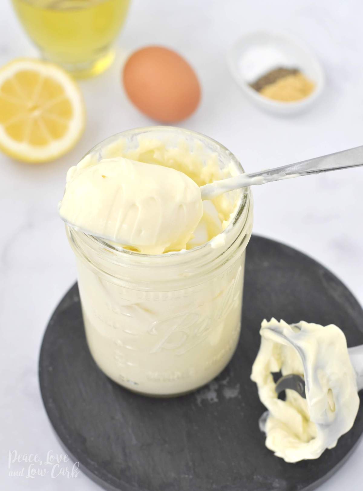 jar of homemade mayo with oil, egg, lemon, mustard, salt, pepper, and an immersion blender