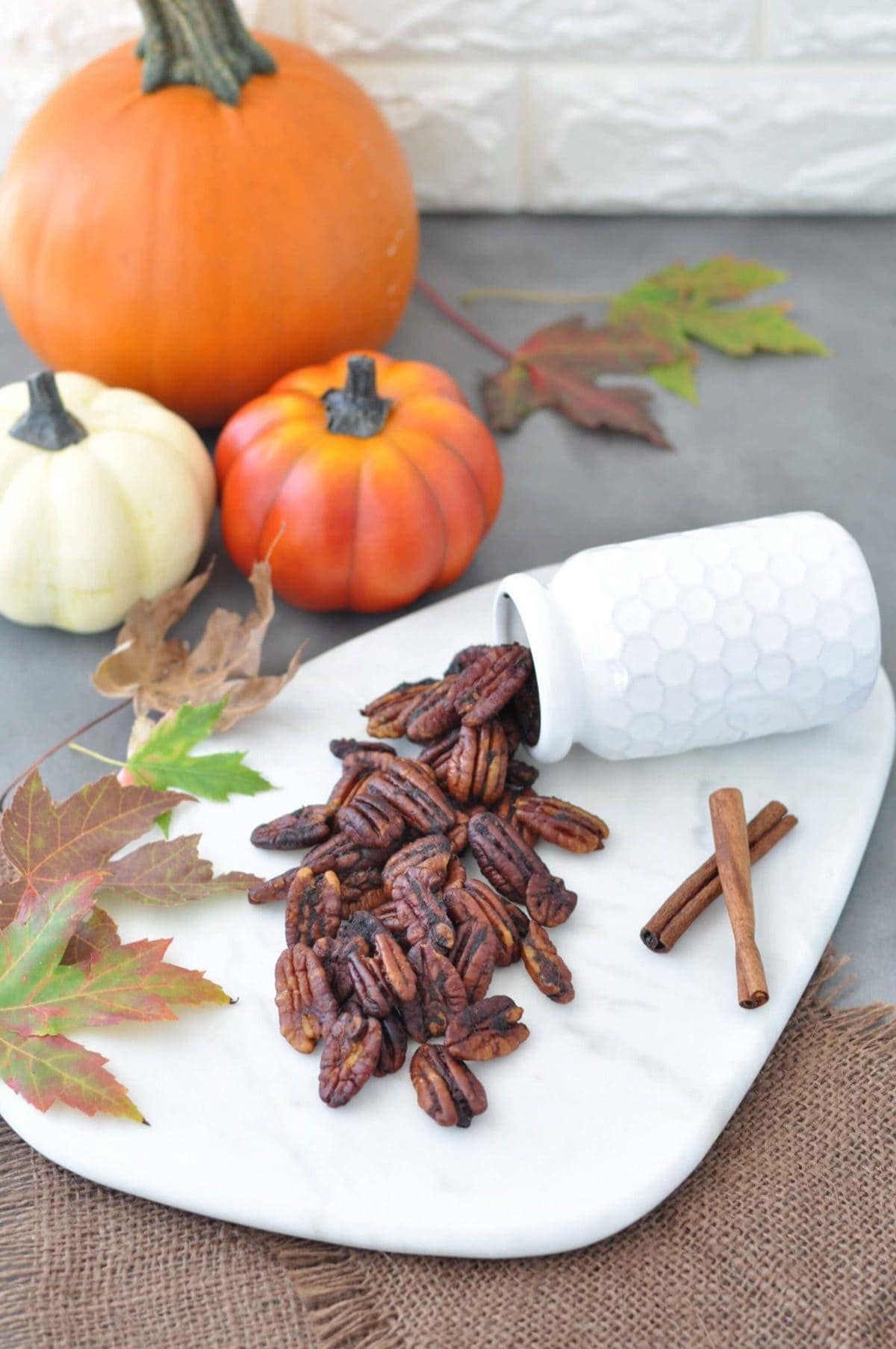 Roasted pecans, surrounded by leaves, cinnamon sticks and pumpkins.