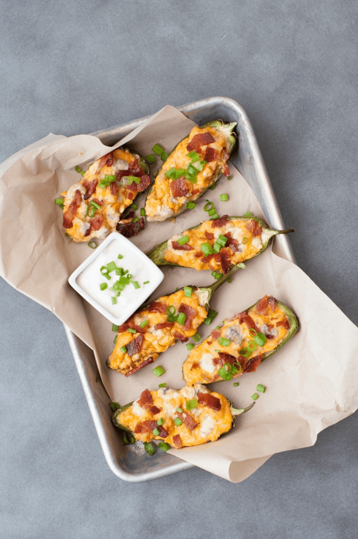 a serving tray, lined with parchment paper filled with low carb jalapeno poppers with buffalo sauce, cheese and bacon