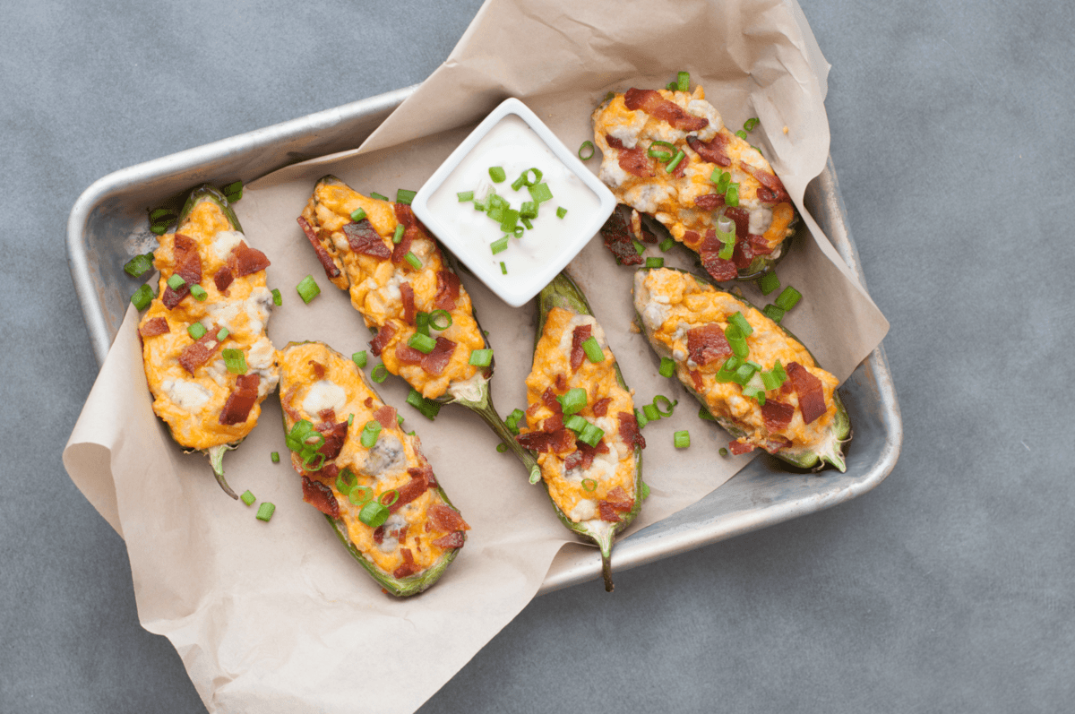 a serving tray, lined with parchment paper filled with low carb jalapeno poppers with buffalo sauce, cheese and bacon