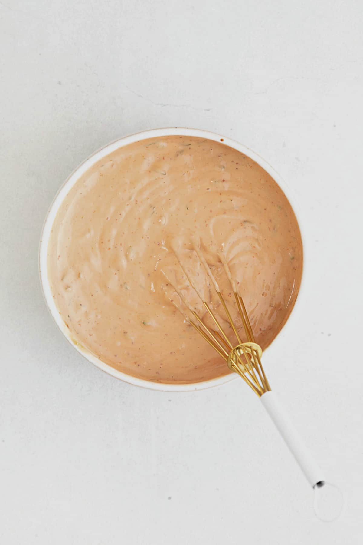 freshly made Russian dressing in a white ceramic bowl with a whisk