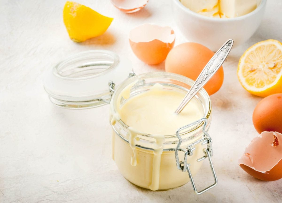 a jar of homemade hollandaise sauce with some of the sauce dripping down the side. 