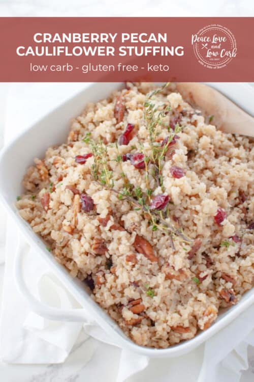 A white casserole dish full of a low carb stuffing made with cauliflower rice, dried cranberries and pecans.