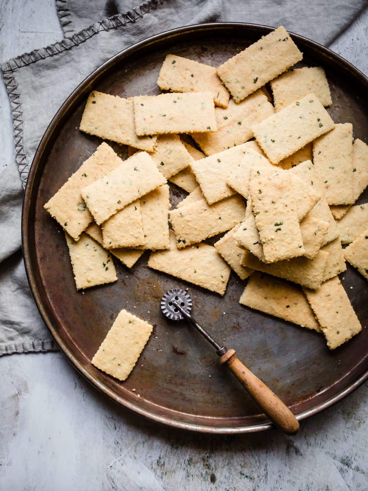 a pizza pan full of garlic parmesan keto crackers with a gray towel next to it.