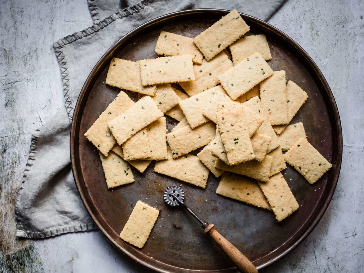 a pizza pan full of garlic parmesan keto crackers with a gray towel next to it.