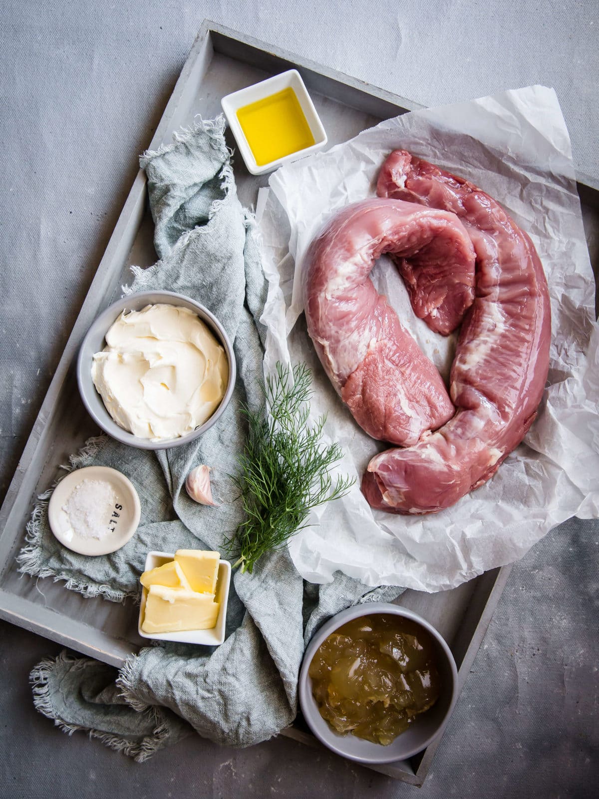 ingredients to make pork tenderloin with creamy dill sauce - pork, sour cream, dill, olive oil garlic, chicken stock