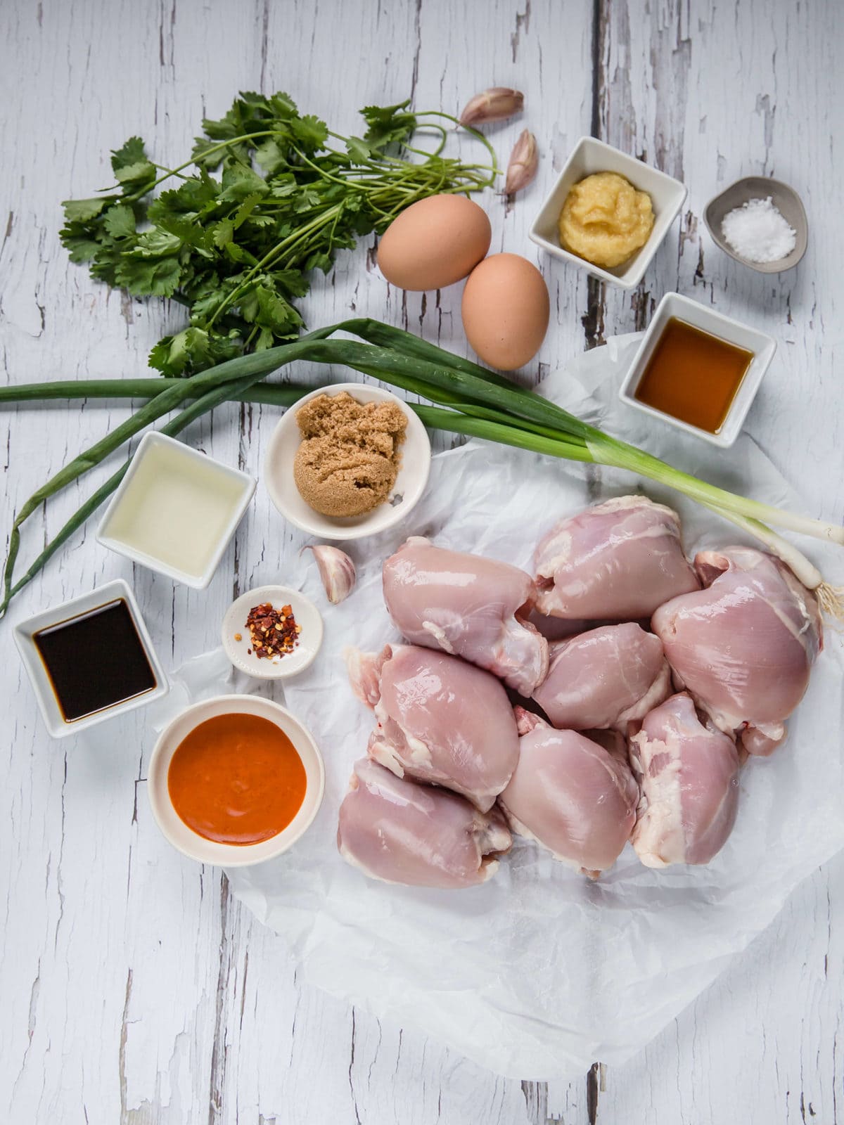 ingredients laid out to make asian chicken meatballs - chicken, sriracha, cilantro, green onions, garlic, ginger, sesame 