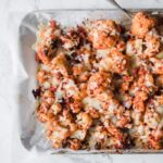 sheet pan lined with parchment paper and topped with roasted cauliflower, baked with cheese and pizza sauce