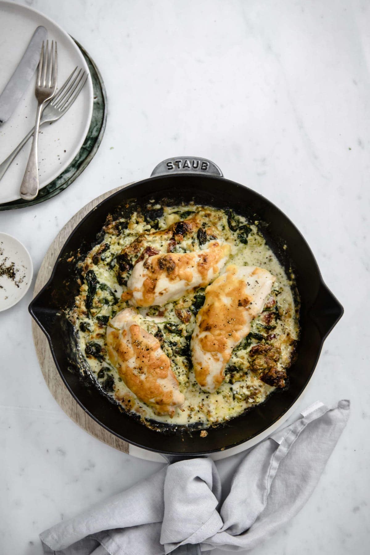 a cast iron skillet with a broccoli and cheese stuffed chicken  breast, covered with cheese and spices