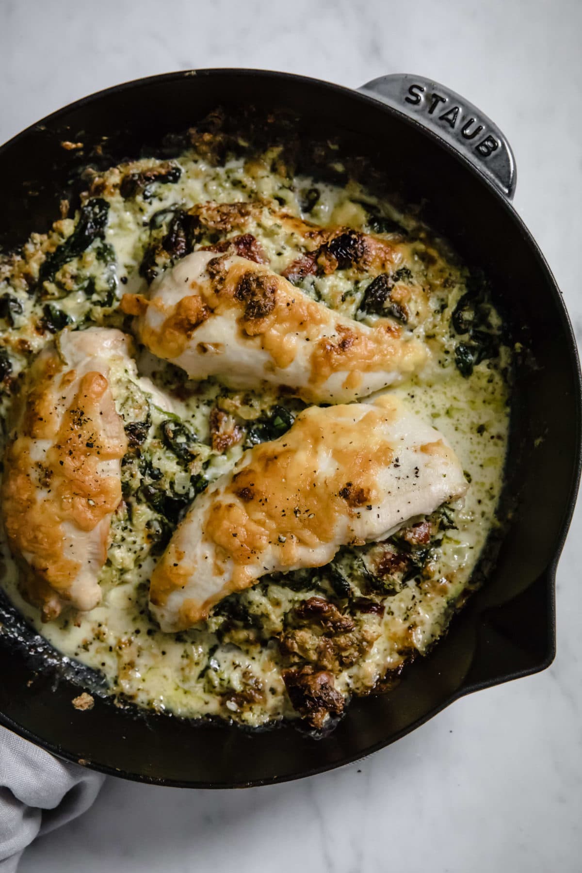 a cast iron skillet with a broccoli and cheese stuffed chicken  breast, covered with cheese and spices