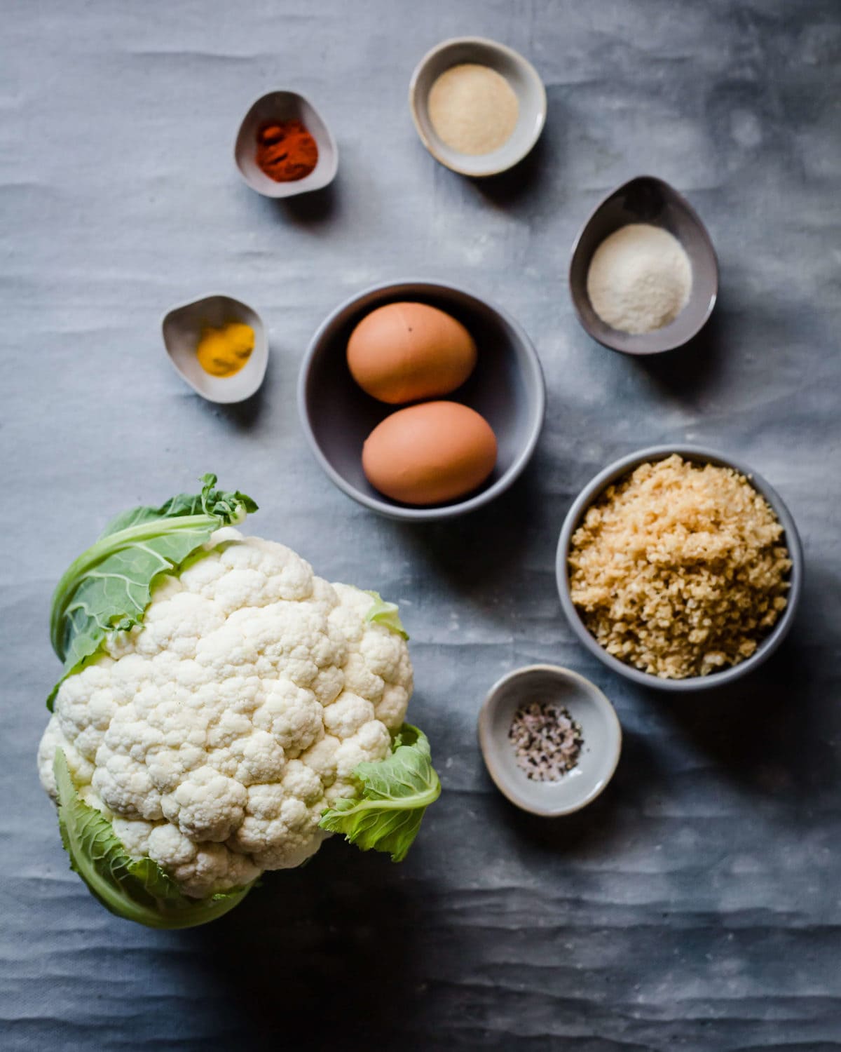 Ingredients laid out to make a chicken fried cauliflower - cauliflower, crushed pork rinds, seasonings, and eggs. 