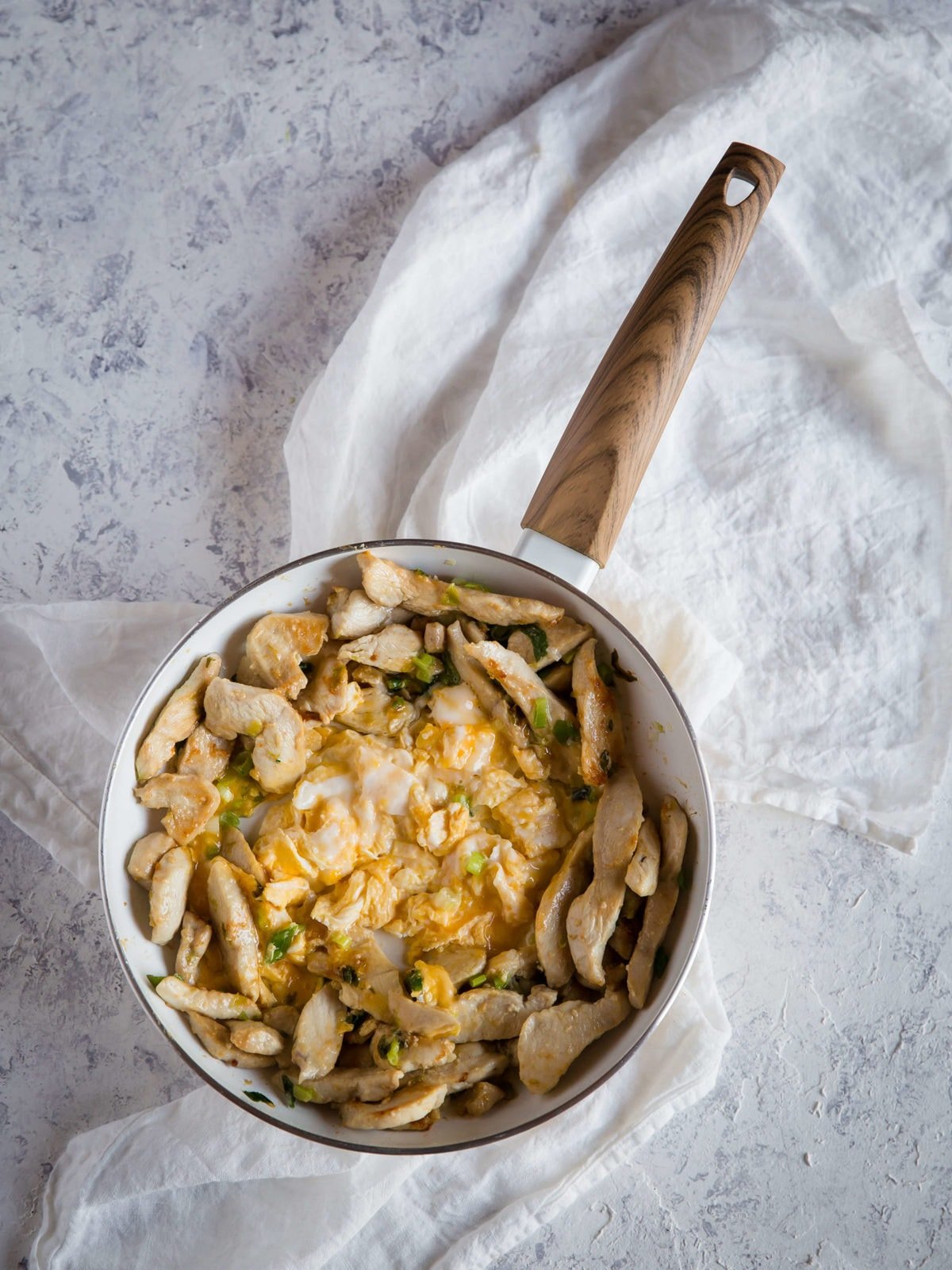 uma frigideira com frango salteado, cebolinha verde, alho e ovos mexidos para uma receita Pad Thai