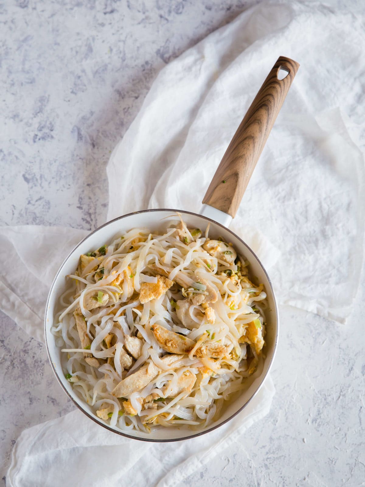 a skillet with sautéed chicken, green onions, garlic, and scrambled eggs and shirataki for Pad Thai