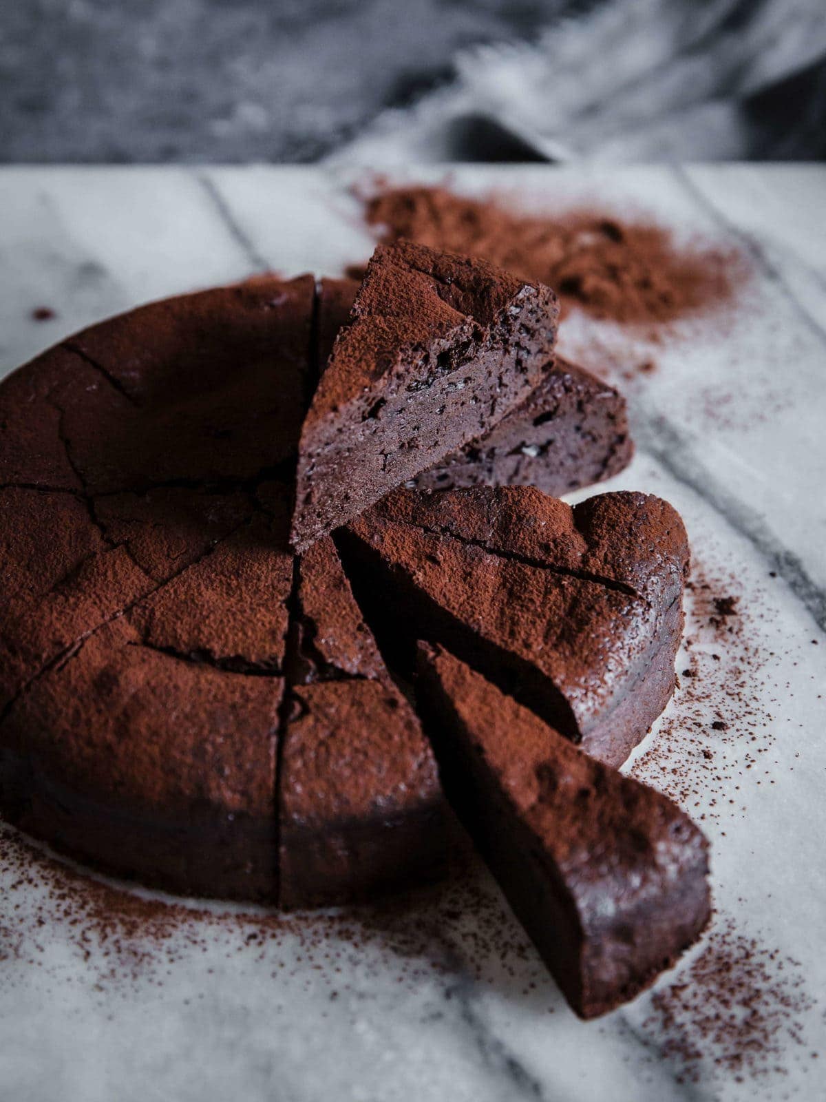 flourless chocolate cake, sliced into 12 slices - with two slices pulled out and dusted with cocoa powder