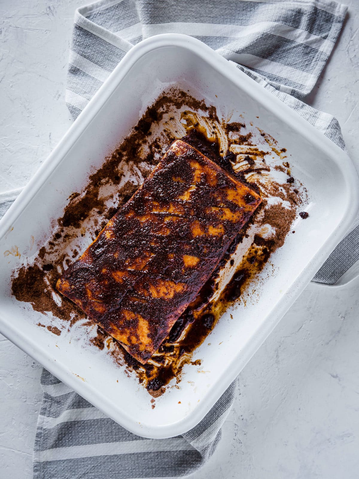 pork belly in a white baking dish, rubbed down with olive oil and coffee barbecue dry rub