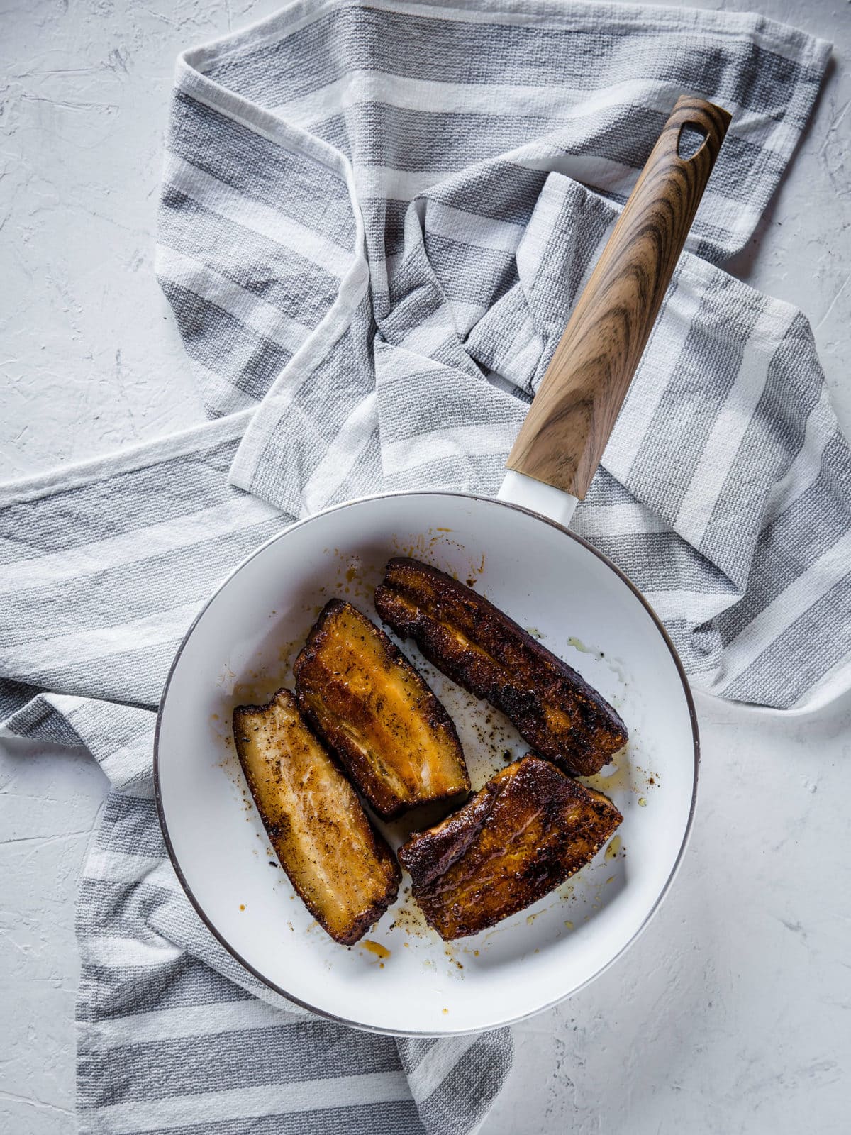 sliced coffee bbq pork belly searing in a white skillet