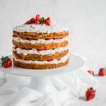 Keto Strawberry Shortcake with 4 layers of cake, whipped cream, and strawberries. The cake sits on a white cake stand.