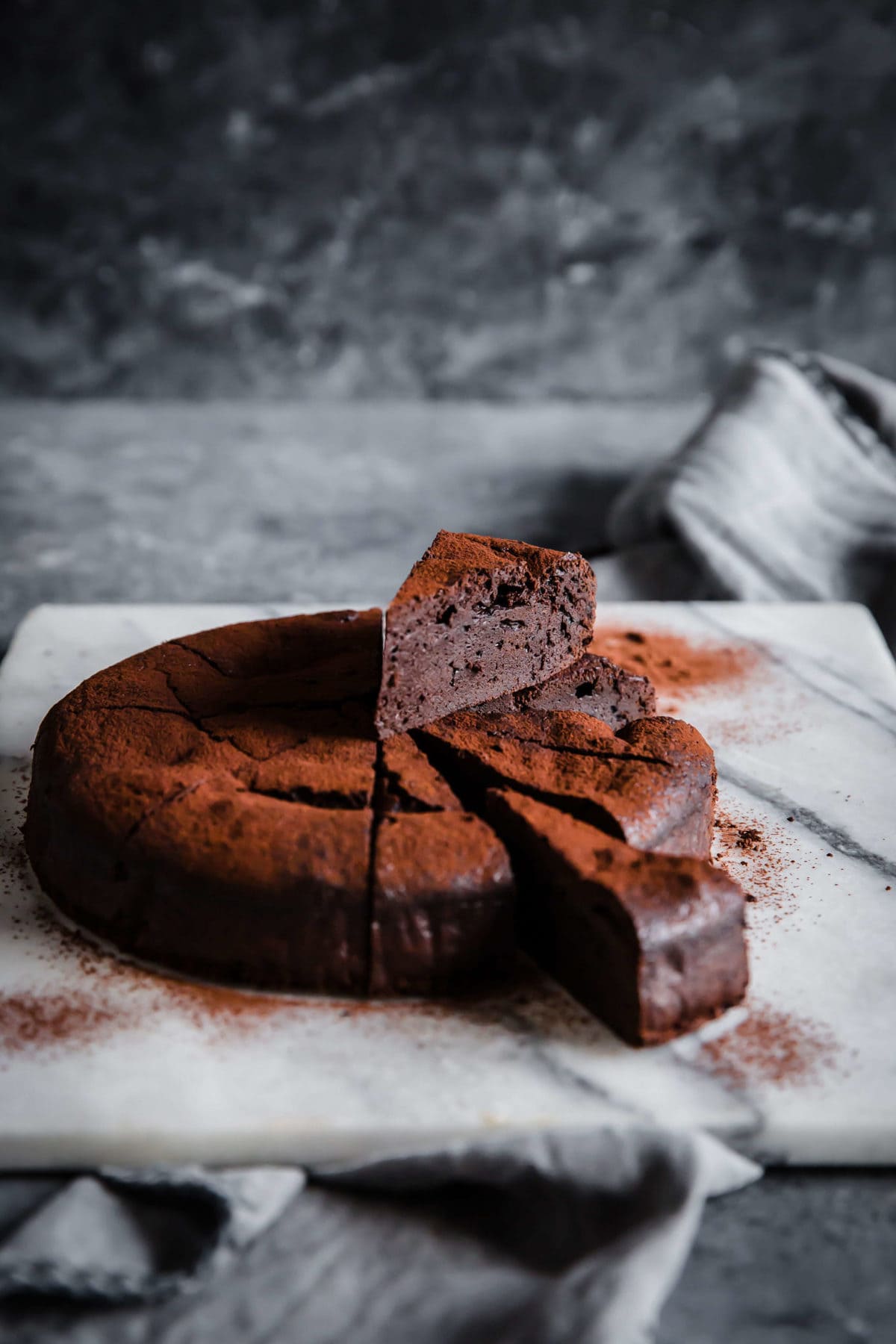 flourless chocolate cake, sliced into 12 slices - with two slices pulled out and dusted with cocoa powder