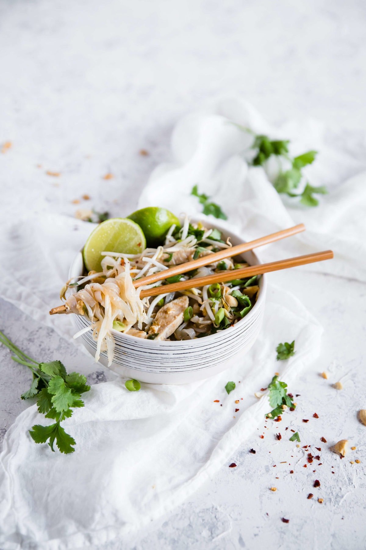 keto Pad Thai, podawane w białej ceramicznej misce z drewnianymi pałeczkami i przyozdobione klinami limonki