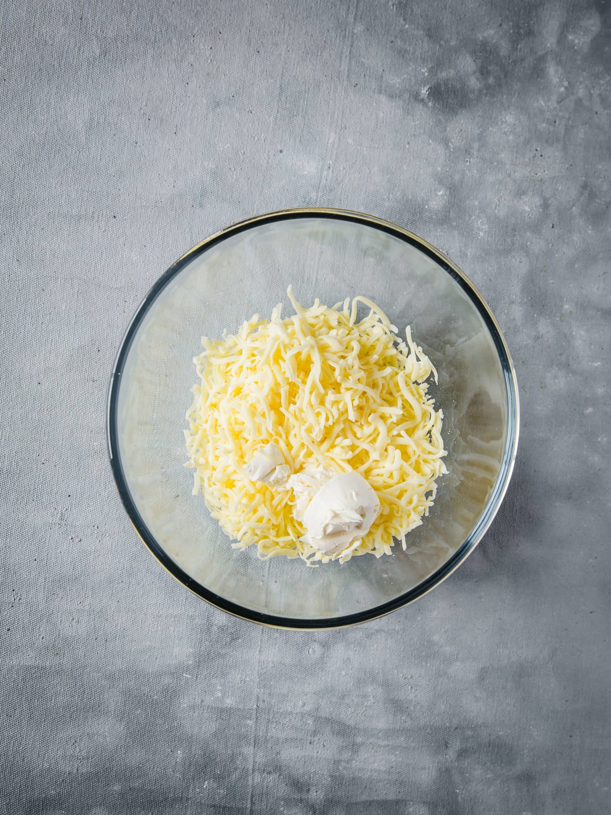 Mixing bowl with shredded mozzarella cheese and cream cheese in it 